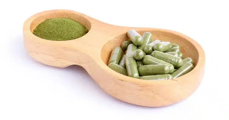 Kratom Capsules and powder in wooden bowl