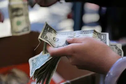Person holding out a crumpled stack of $1 bills